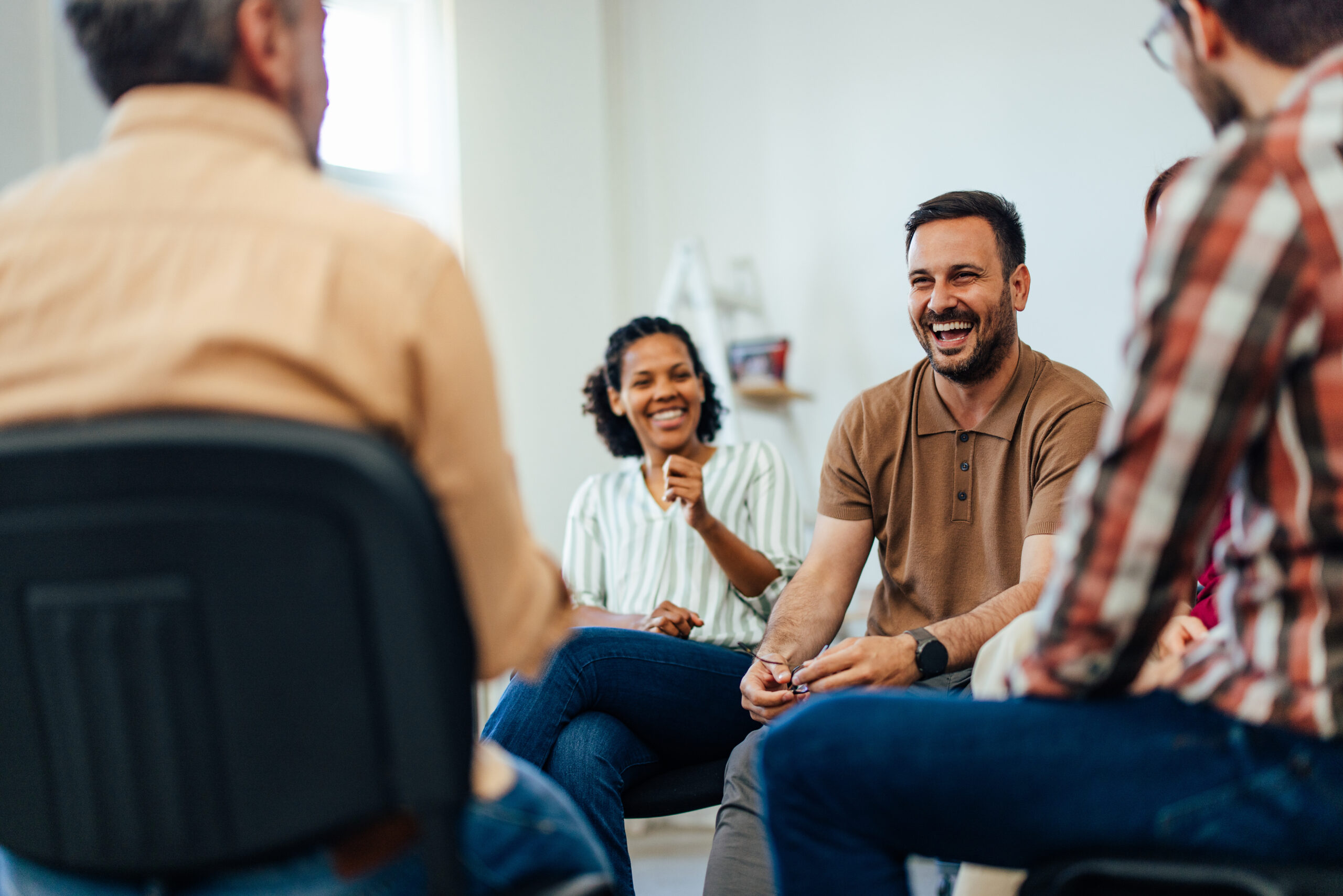 An adult man, looking happy, talking with random people from the